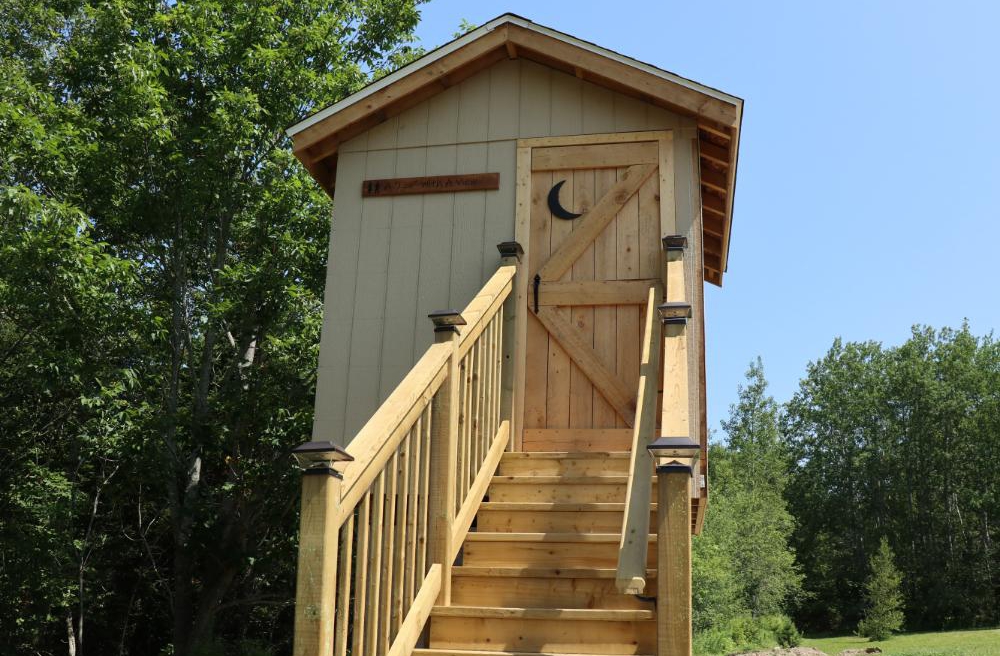 Private bathroom building near Cherry Tent at forest glamping site in Nova Scotia
