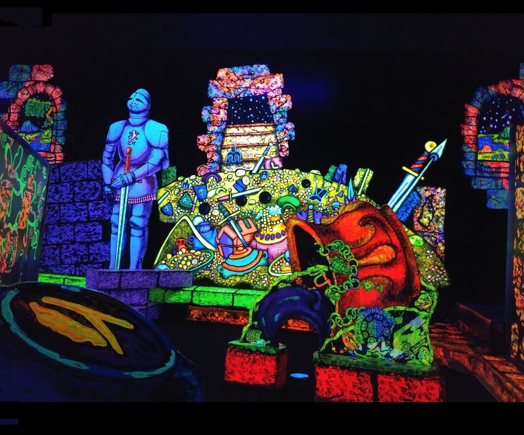 Glow-in-the-dark mini golf course at Putting Edge Halifax featuring neon knight and treasure theme under blacklight.